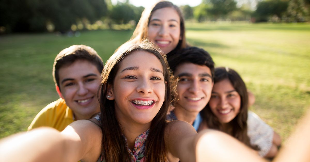teens take a group selfies, one teen wearing a Broken bracket on braces