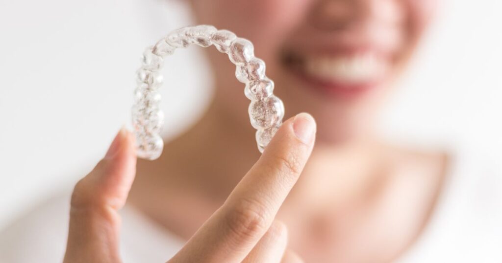 adult holds up aligner after learning how to clean Invisalign